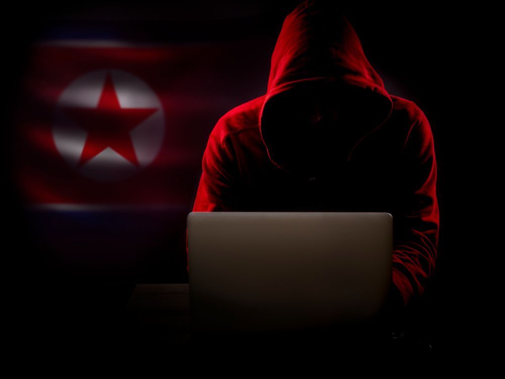 North Korea hacker in the dark with the country&amp;#039;s flag in the background