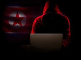 North Korea hacker in the dark with the country's flag in the background