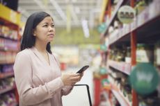 Woman looking at prices while doing shopping in supermarket