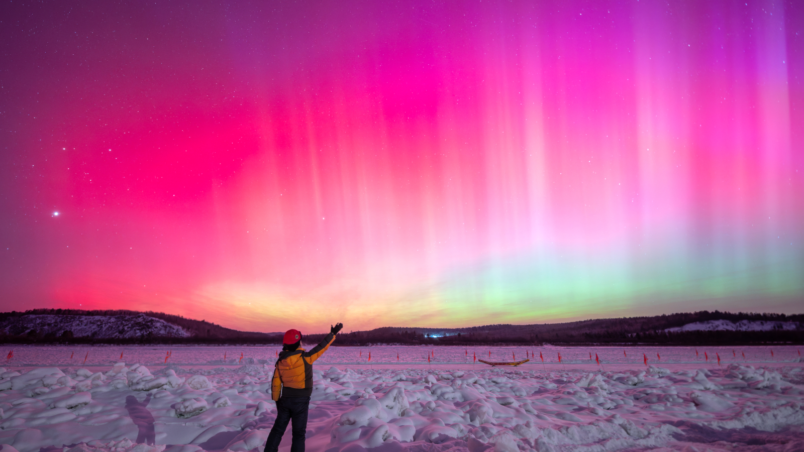 Photo of a person stood in front of pink auroras in China