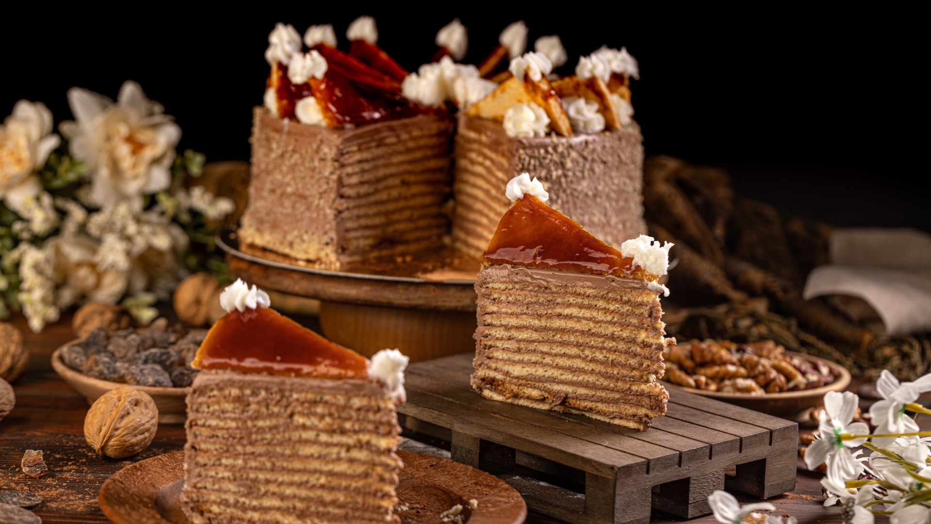 Dobos cake is an elegant layered dessert featuring thin tiers of sponge, rich chocolate buttercream, and a signature, glossy, hard caramel top