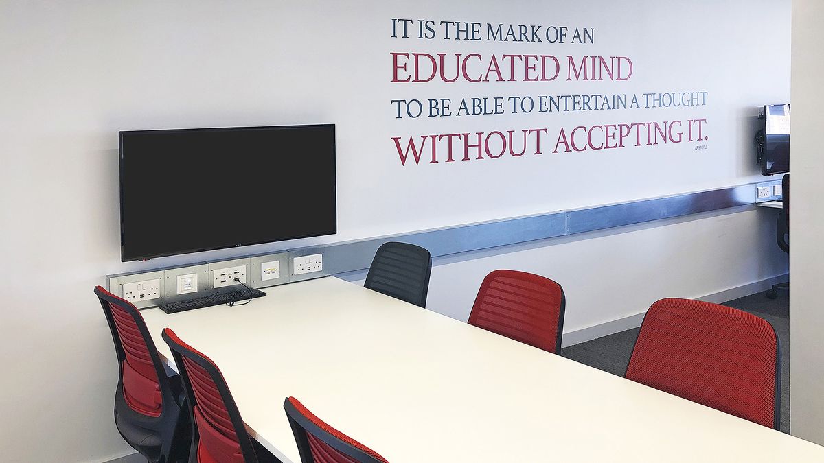 A display at a table with six red chairs is ready for collaborative learning.