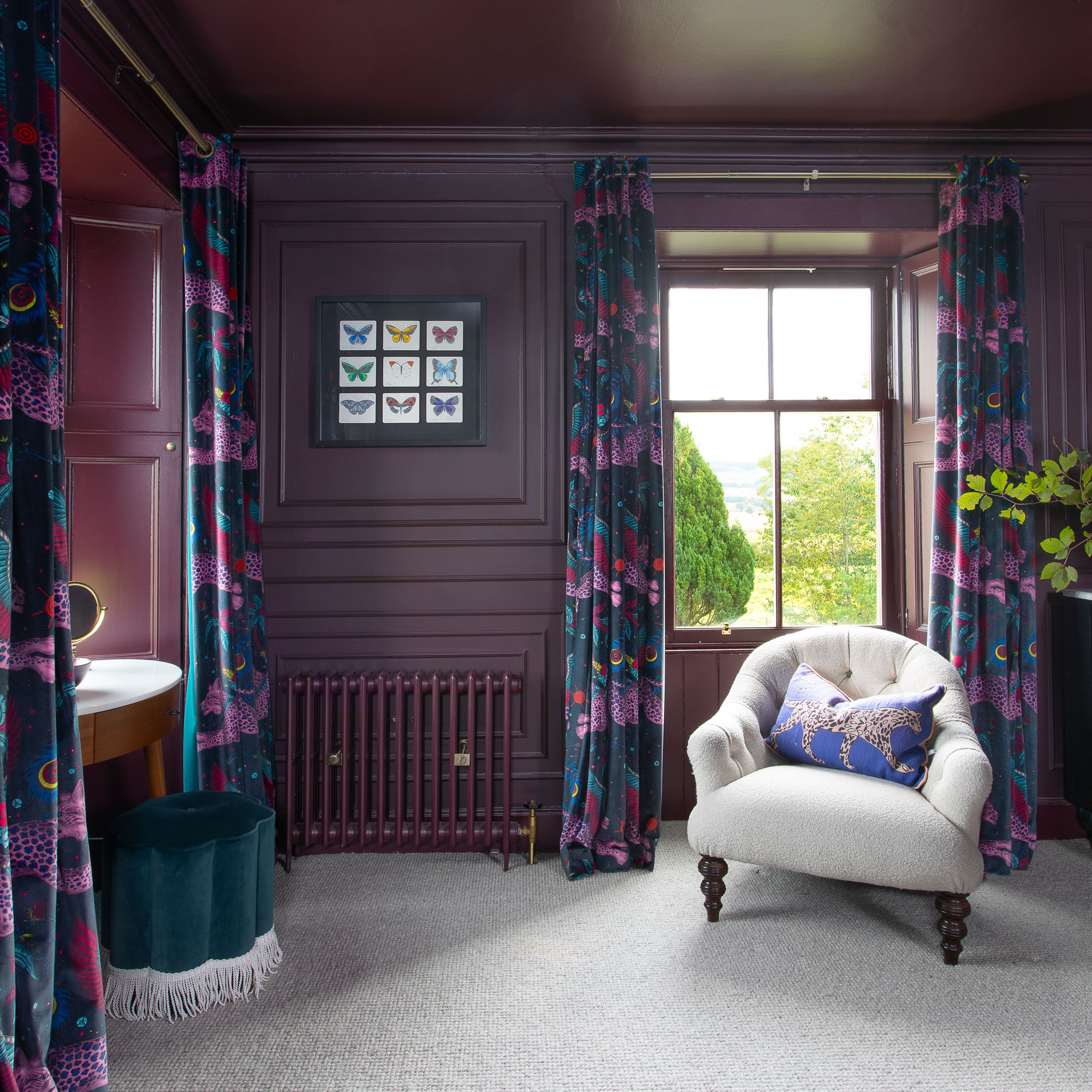 Purple room with matching radiator, grey armchair and blue and purple curtains