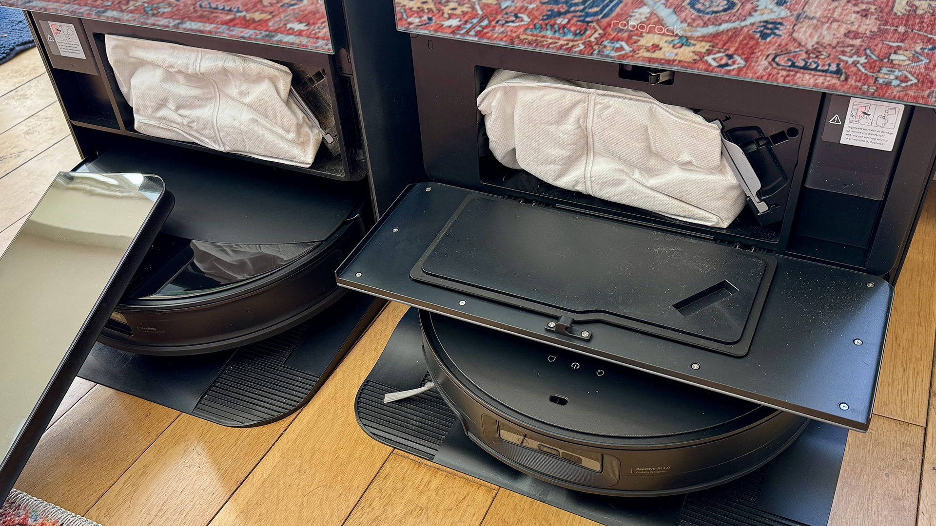 Docks for Roborock Saros 10R and Saros 10 robot vacuums with doors open to show onboard dust bag