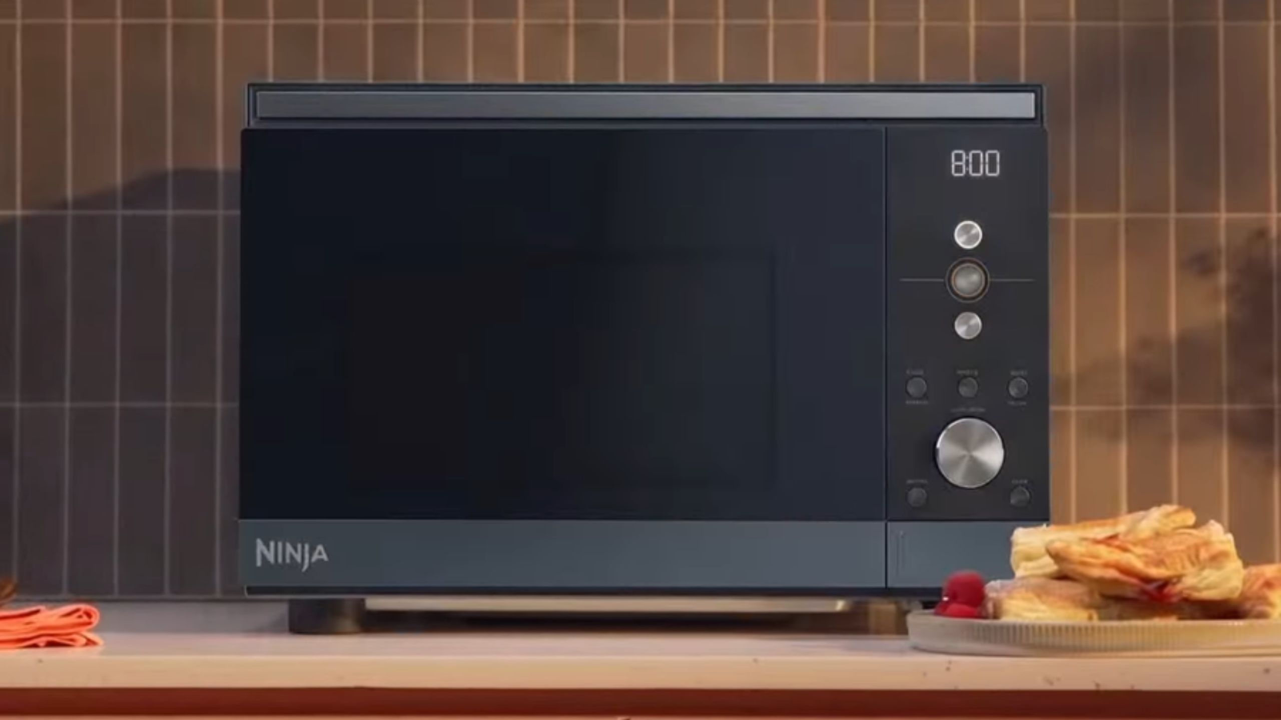 A blue Ninja Crispi Microwave on a warm toned kitchen counter.