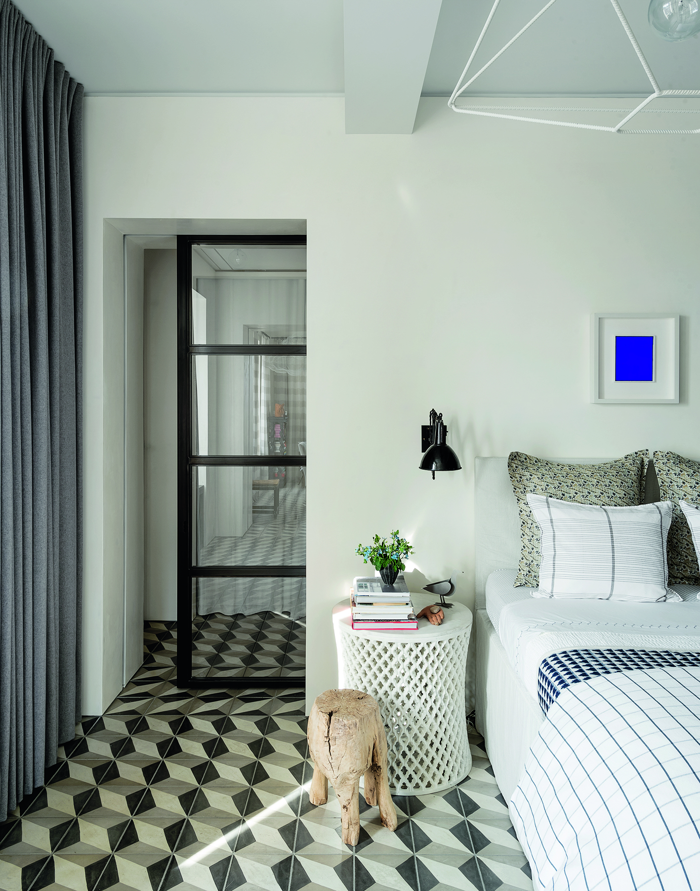 A bedroom with a black framed glass door and a white, gray and black geometric tiled floor