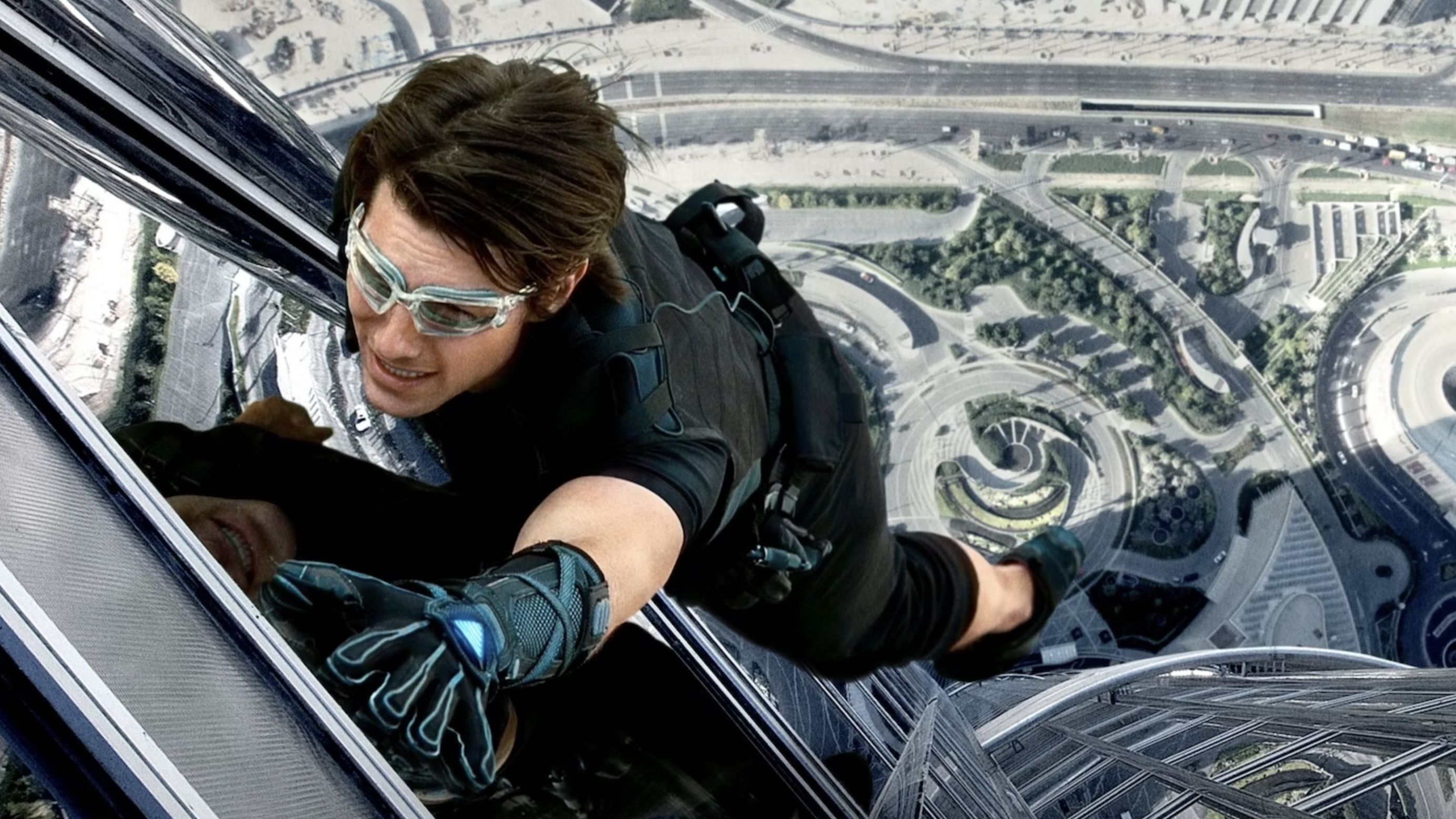 A still from the movie Mission Impossible Ghost Protocol of Tom Cruise as Ethan Hunt scaling a huge skyscraper.