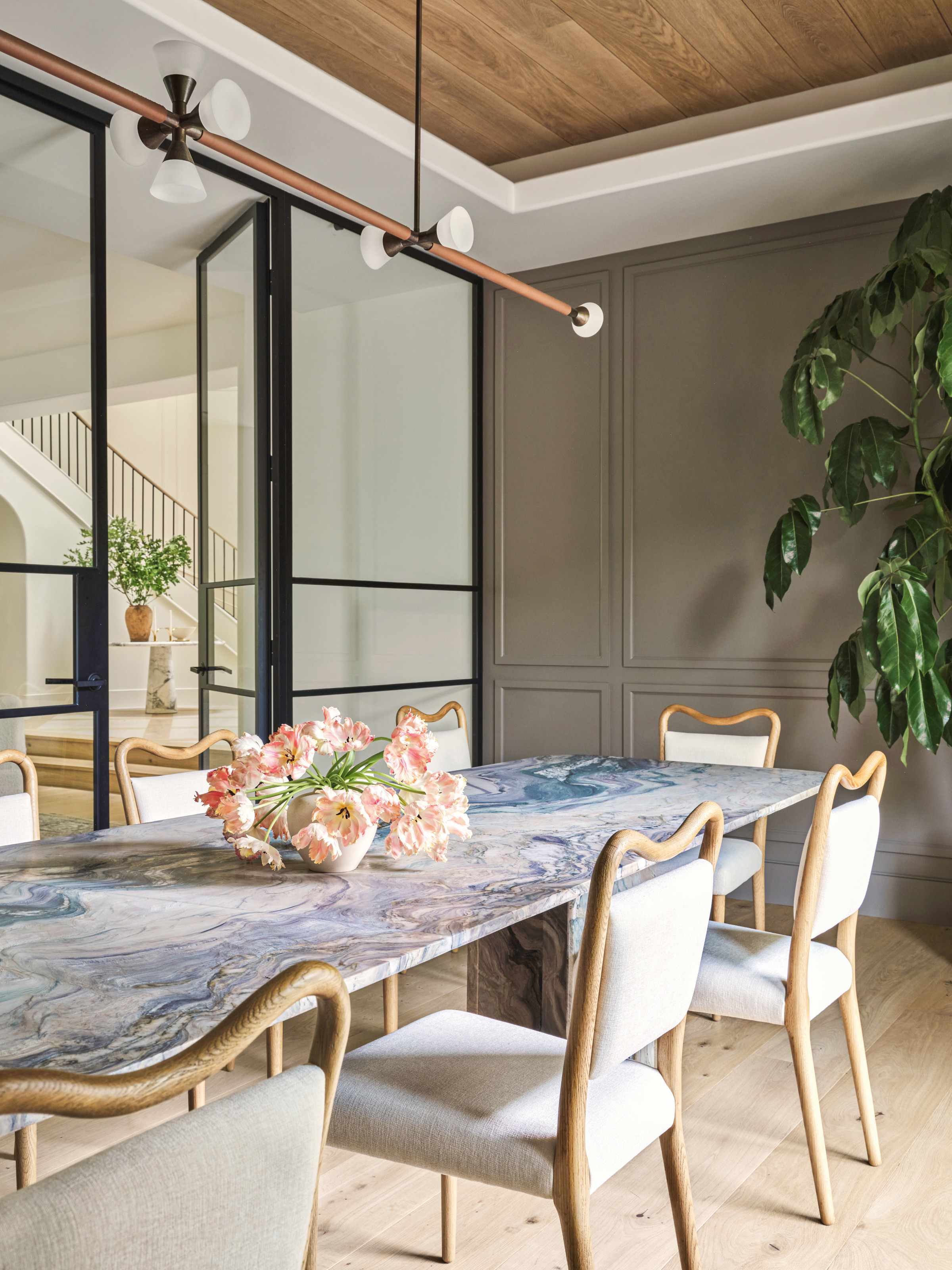 Dining room with grey panelled walls, blue marble dining table and cream upholstered chairs