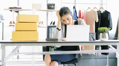 A dress shop owner looks at her computer in dejection.