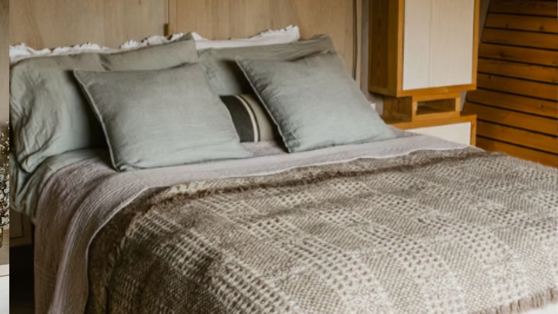 The bed in the Hergest Lee Cabin with a throw and linen pillows