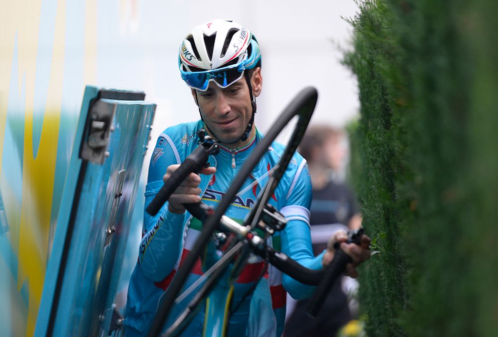 Vincenzo Nibali squeezes through a gap between the team bus and a hedge