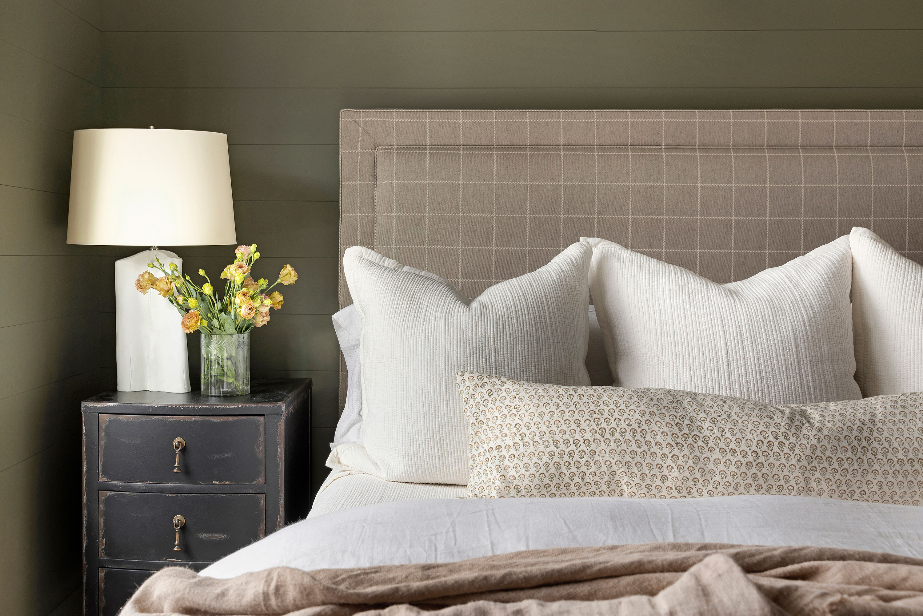 bedhead with green walls checked upholstered bedhead vintage cabinet white lamp and natural bedlinen
