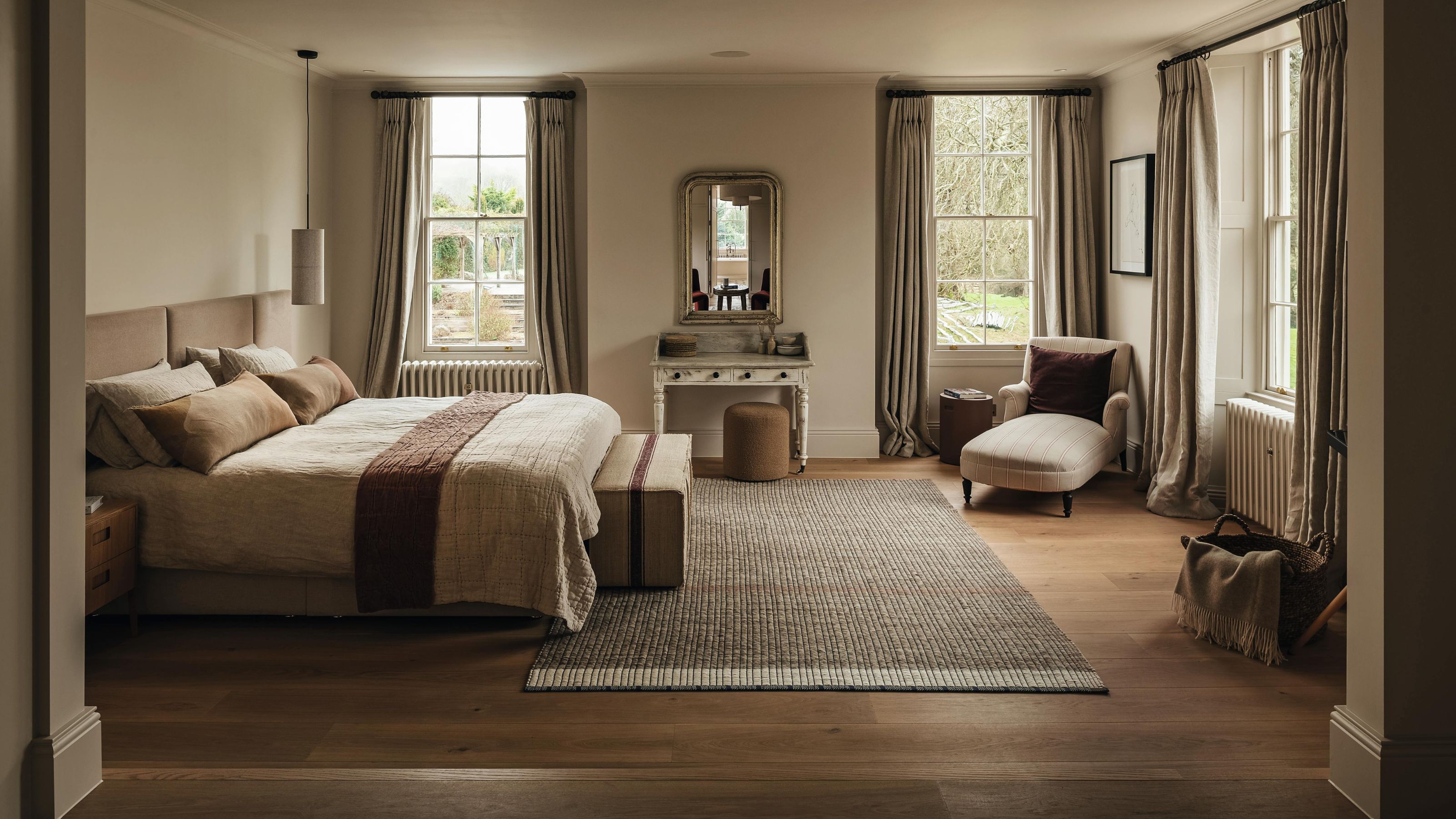 a large neutral main bedroom with three large georgian windows