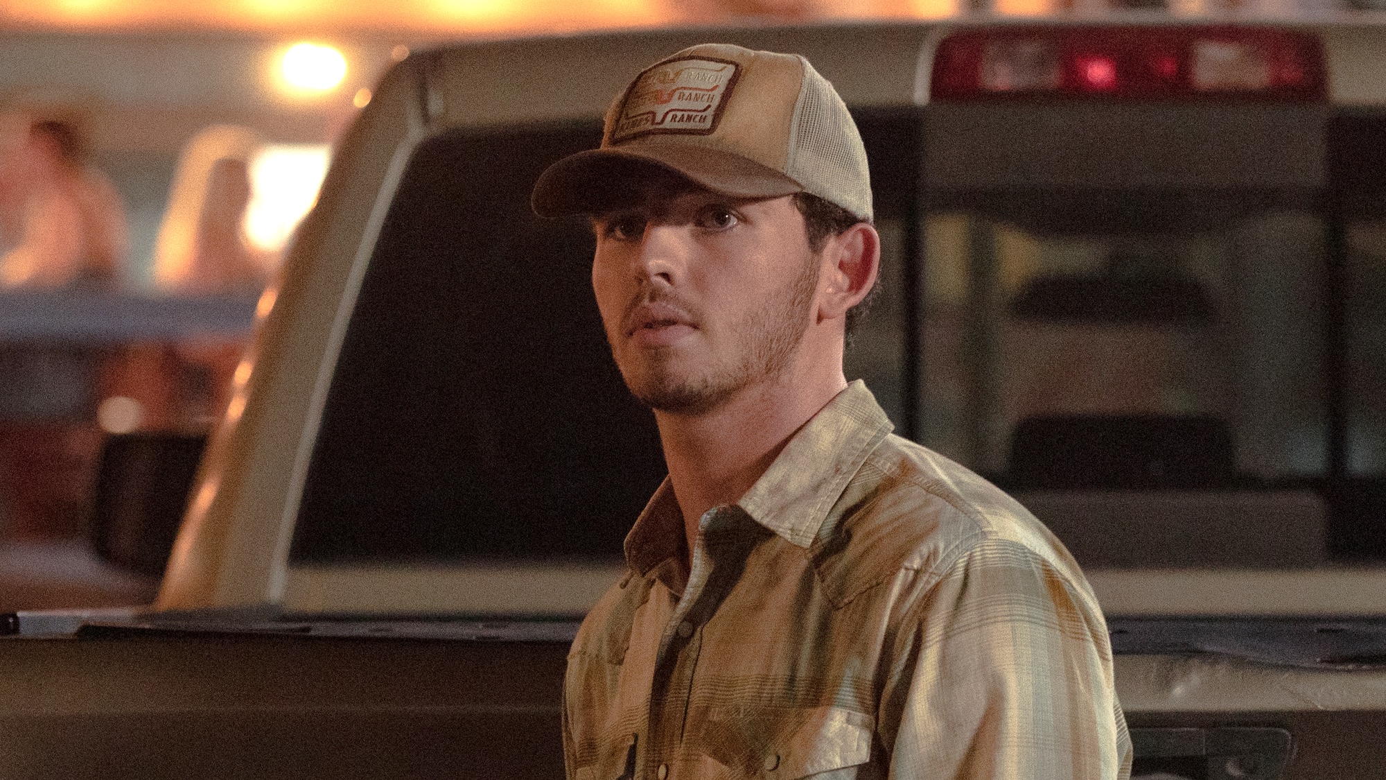 Carter standing behind pick-up truck looking unhappy in Dutton Ranch Season 1