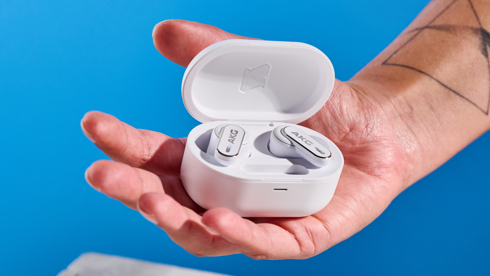 the akg n5 hybrid earbuds by harman in white, shown in their charging case with accessories and without
