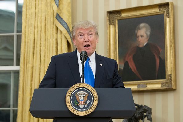 Donald Trump with a portrait of Andrew Jackson behind him.