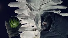 A scientist holds a watermelon in Antarctica. 
