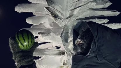 A scientist holds a watermelon in Antarctica.