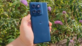 The Motorola Edge 60 in front of a flowery bush.