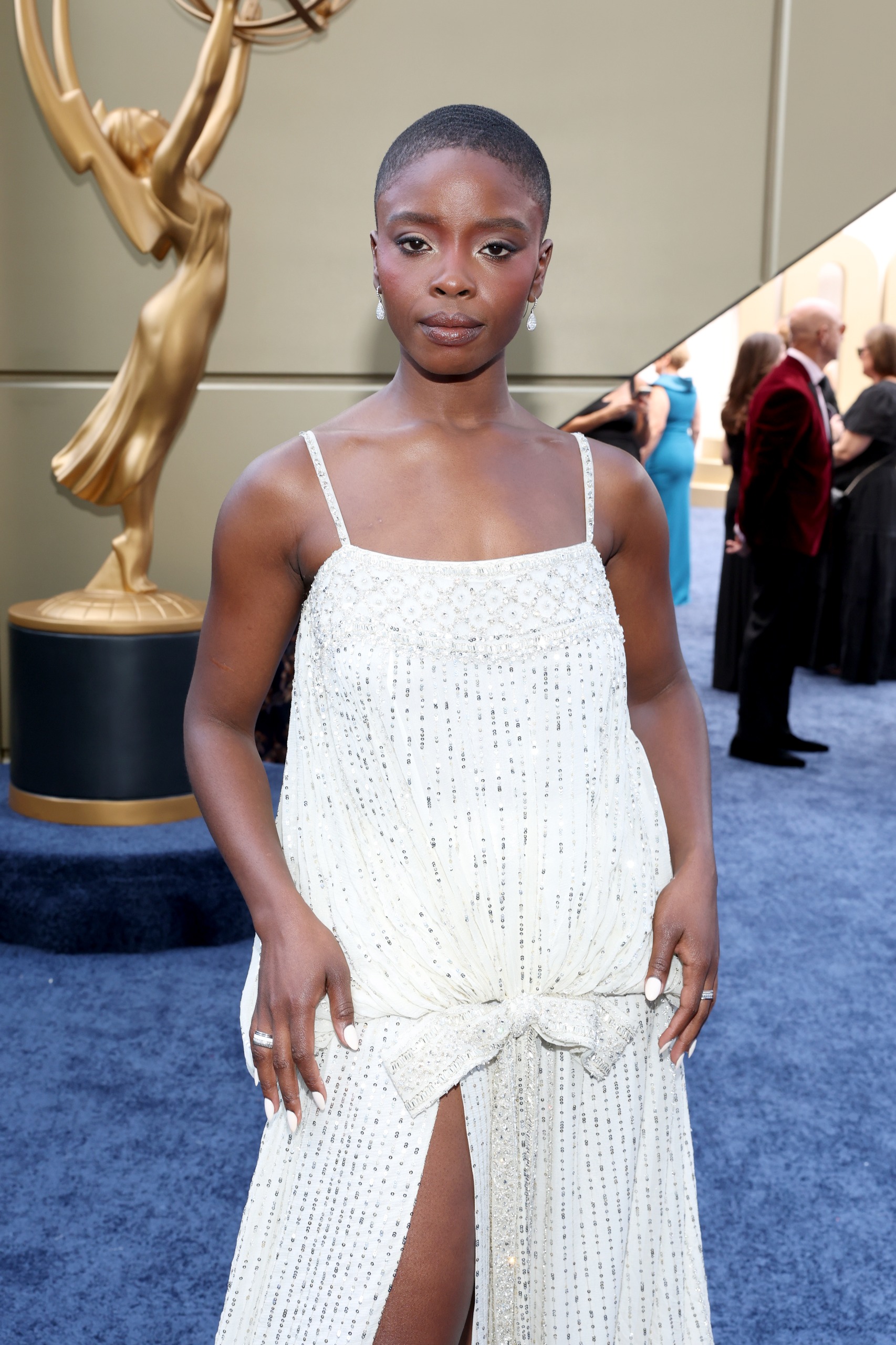 a black woman with short hair in a silver gown on the emmys blue carpet