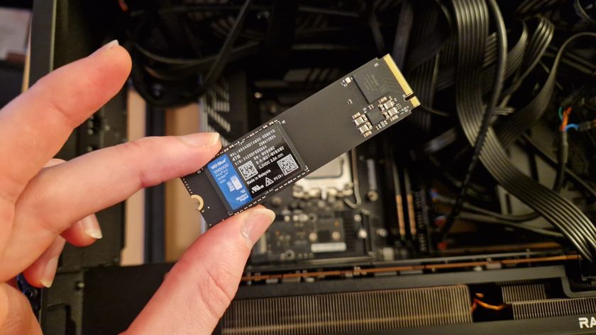 The WD Blue SN5000 4TB SSD being held above a gaming PC by a reviewer