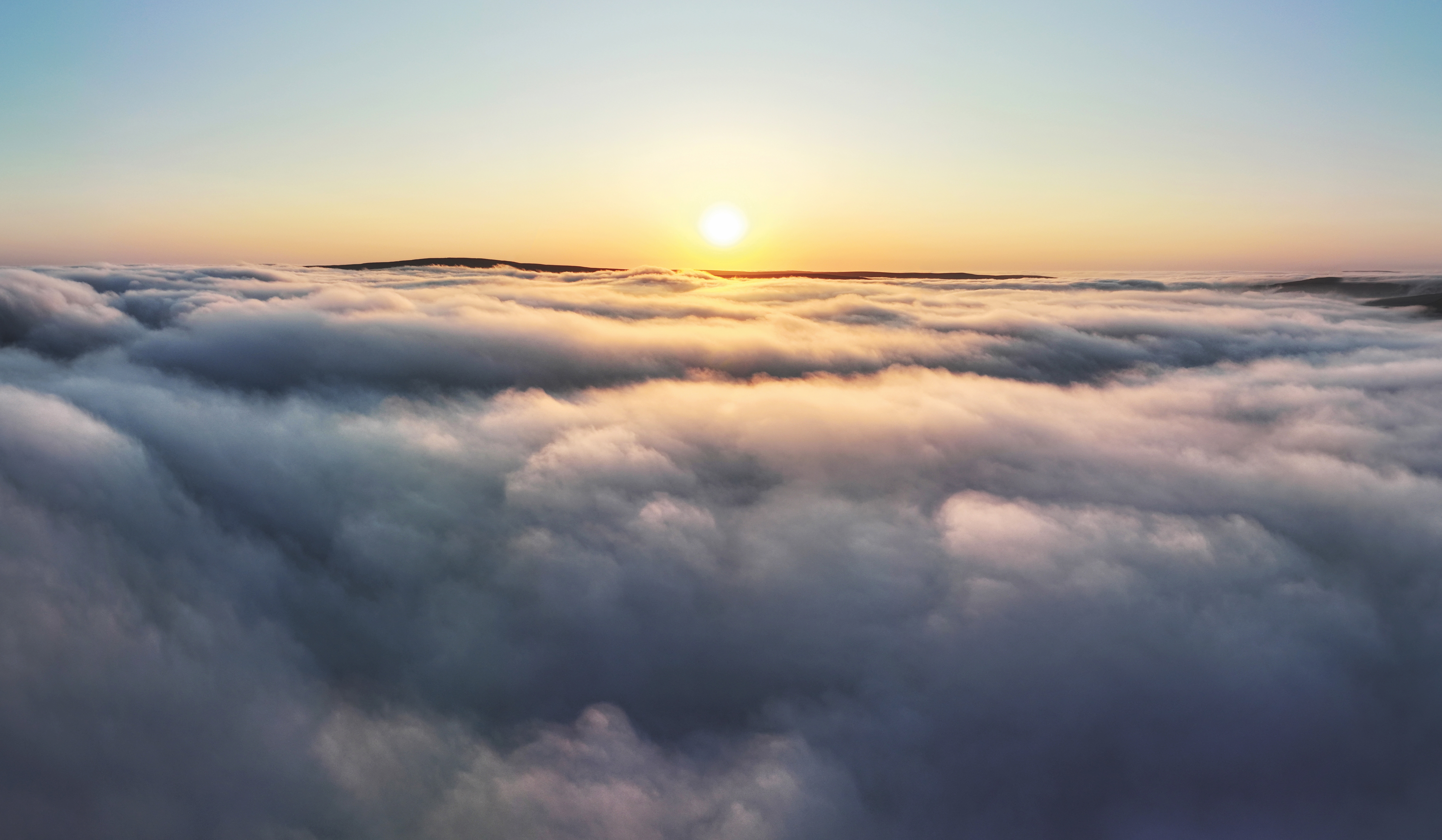 Aerial panorama of a sunrise above thick clouds.