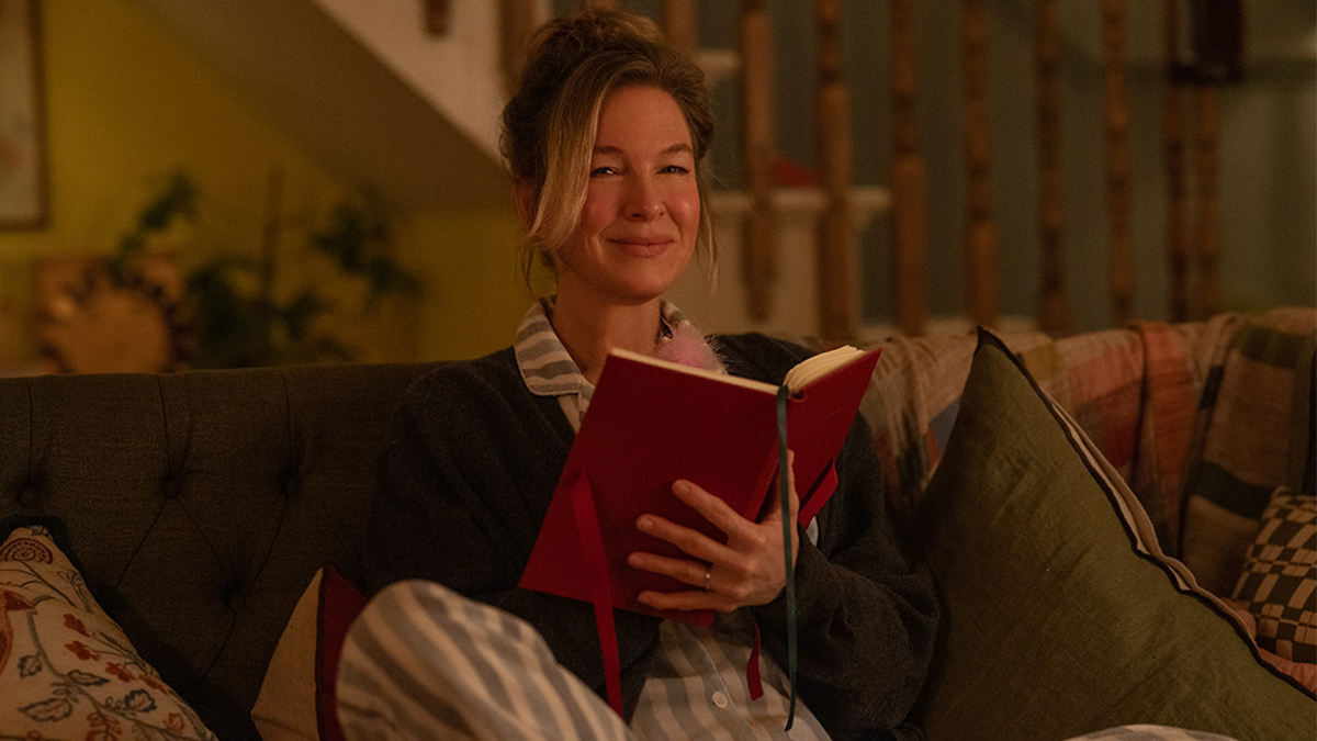 Renée Zellweger as Bridget Jones, sitting in pyjamas on her sofa, writing in her diary in new movie Bridget Jones: Mad About the Boy