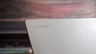 The Zenbook S 16 photographed on a dark marble surface with potted plants in the background.