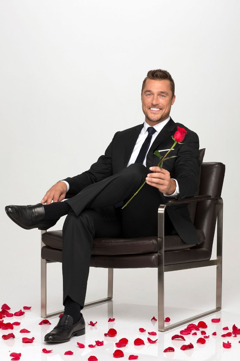 Sitting, Suit, Red, Formal wear, Tuxedo, Furniture, Businessperson, Footwear, Tie, Shoe,