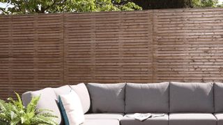 modern grey outdoor sofa with single slatted wooden fence