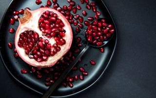 Half a pomegranate with scattered seeds on a plate