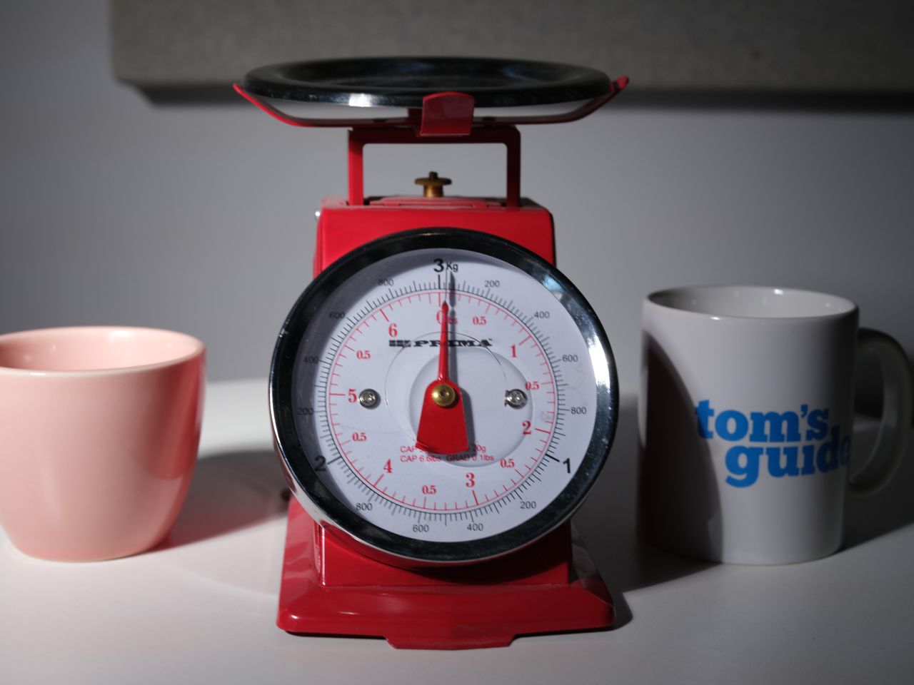 An image of a red scale and two coffee cups, one with the Tom's Guide logo