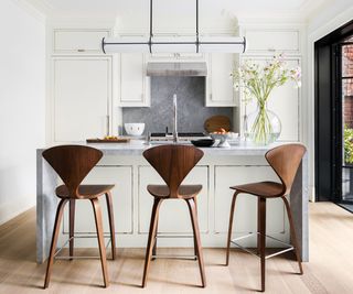kitchen with island and wooden backed bar stools with white cabinets