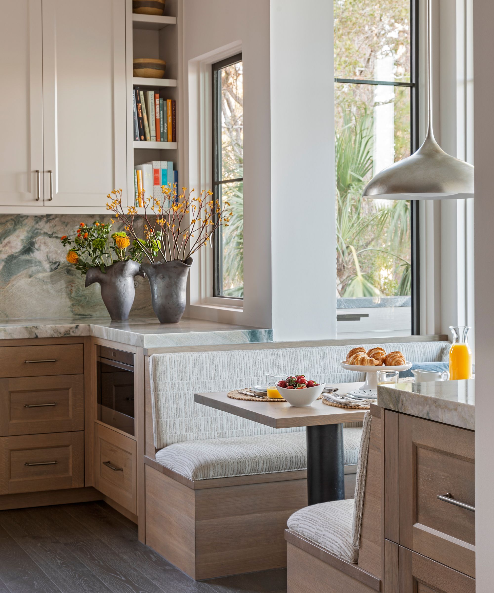A wood and white kitchen with a banquette eat-in area tucked into the bay window