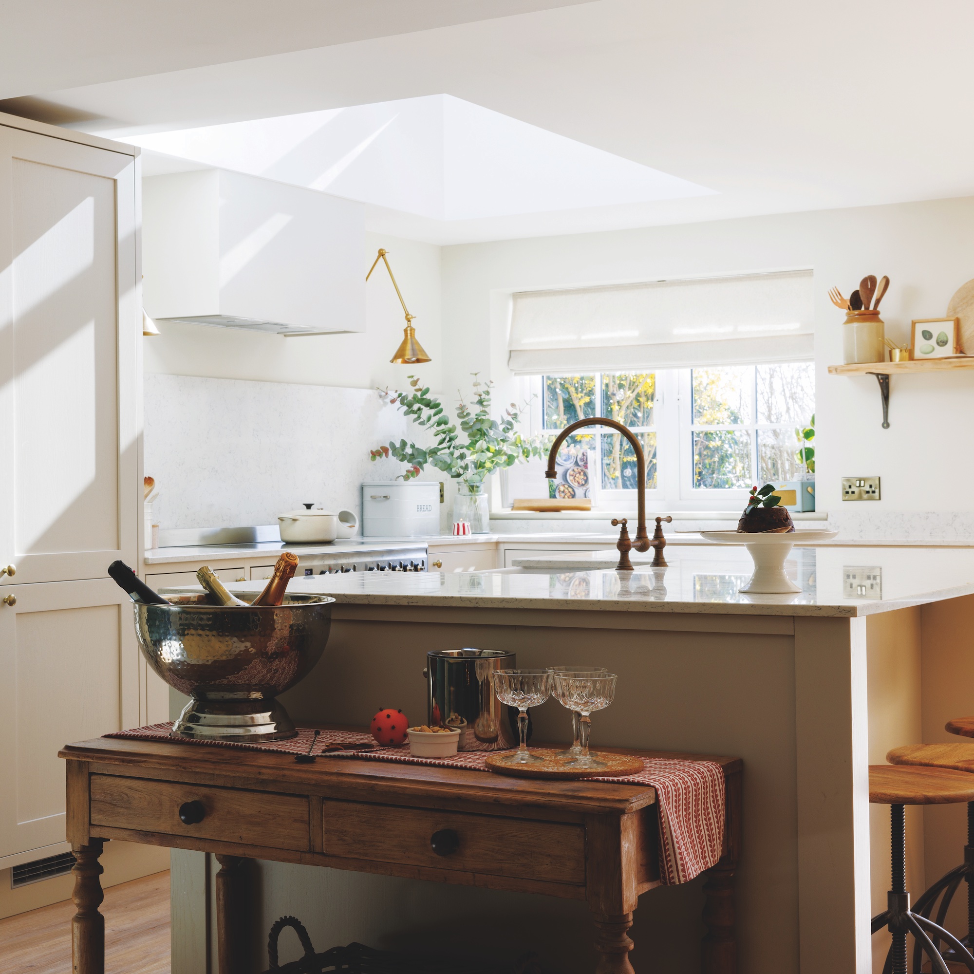 kitchen with white units and large island with console table next to it with champagne bucket