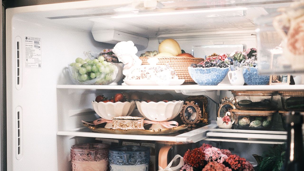 Open refrigerator filled with bowls, foods, and decorative items 