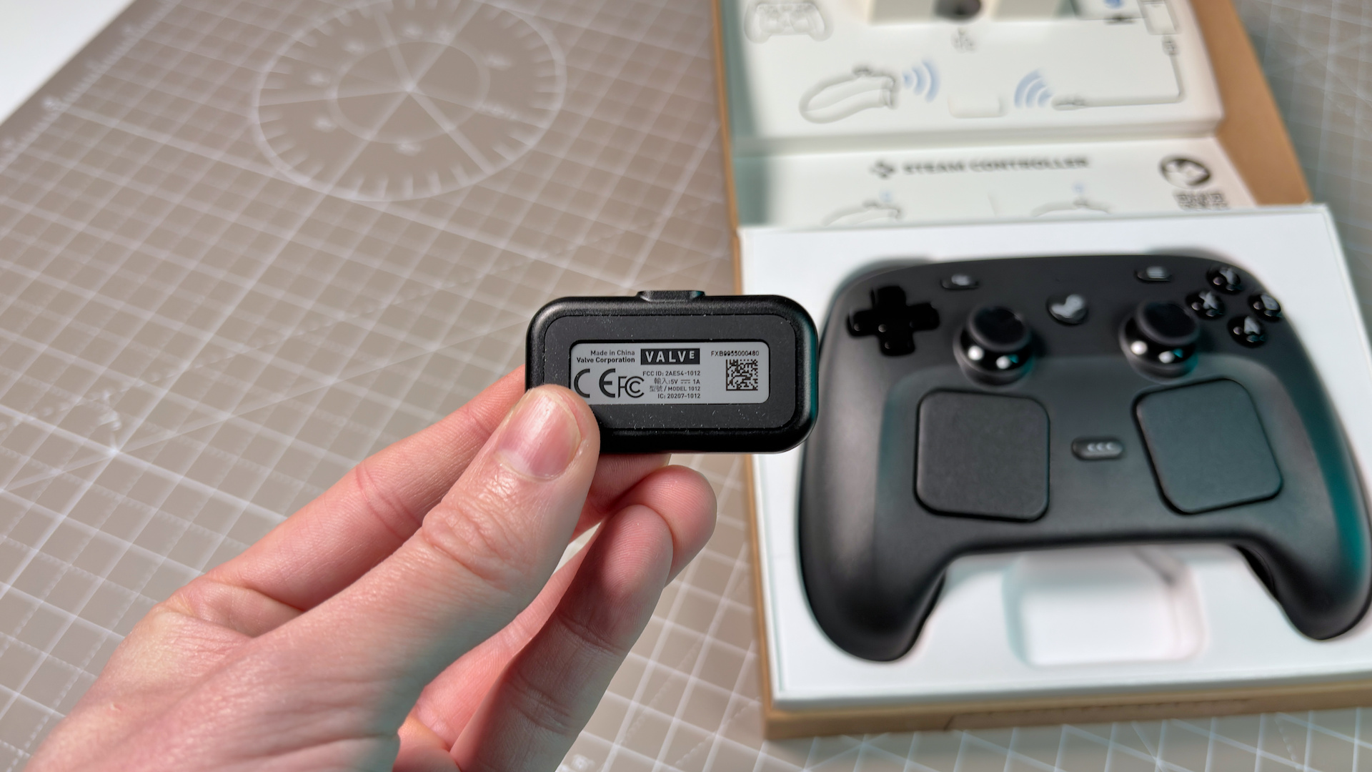 The Steam Controller on a desk with the Puck in the foreground