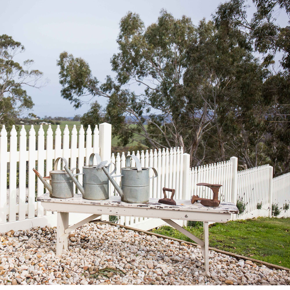 garden area with white picket fence and watering cans