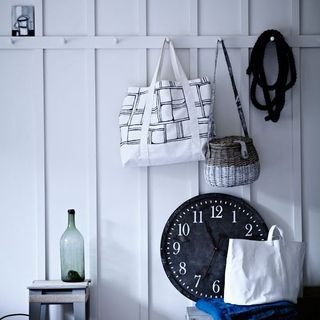 hallway with white clapboard walls and hanging pegs