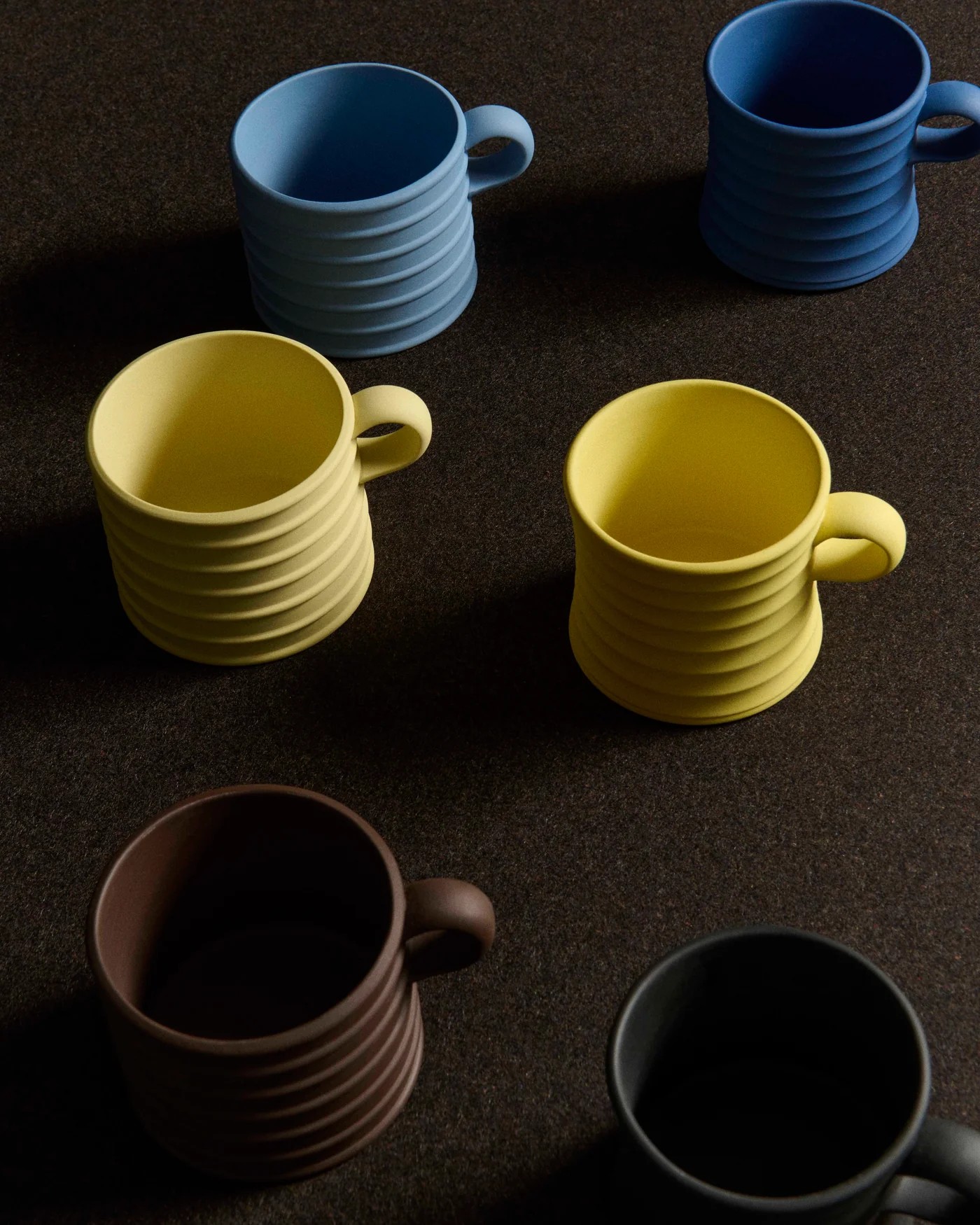 Image of brown, butter yellow, and blue mugs on a dark background