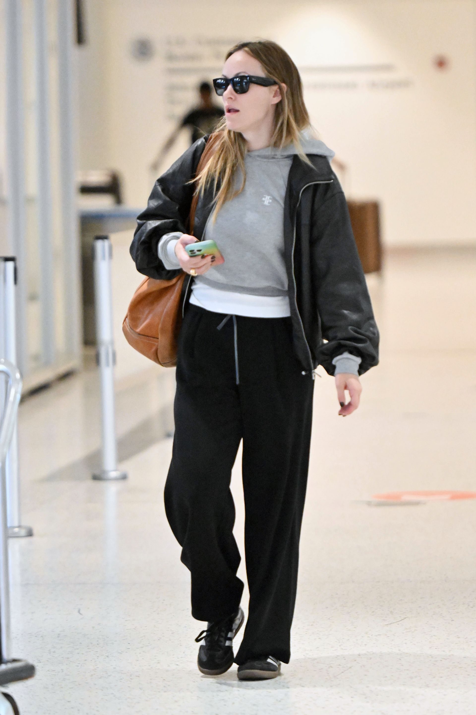 09/20/2025 Olivia Wilde spotted arriving at JFK airport in New York City. The 41 year old American actress wore a grey jumper paired with black joggers and Adidas Samba sneakers.