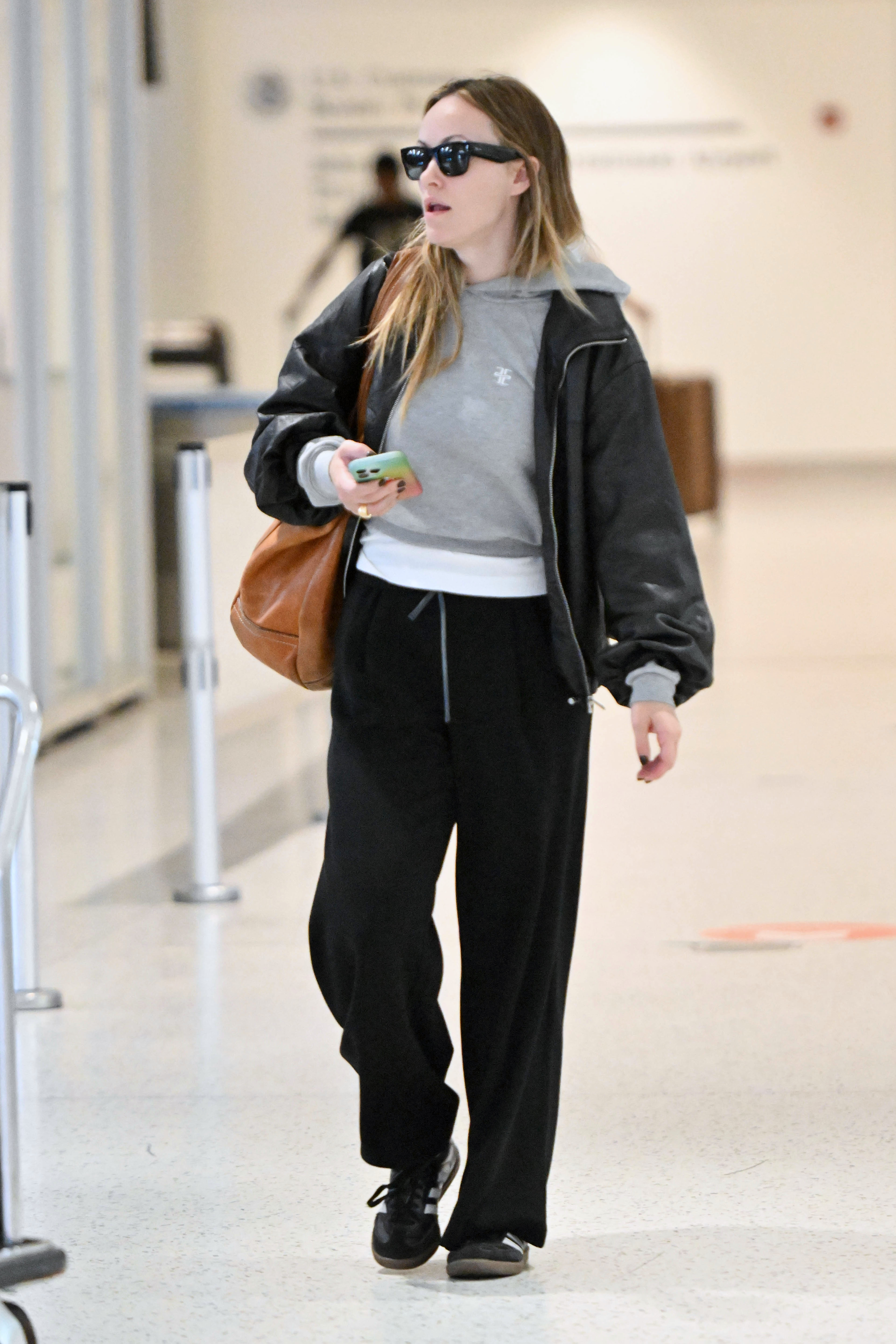 09/20/2025 Olivia Wilde spotted arriving at JFK airport in New York City. The 41 year old American actress wore a grey jumper paired with black joggers and Adidas Samba sneakers.