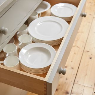 white open drawer with white cups and plates