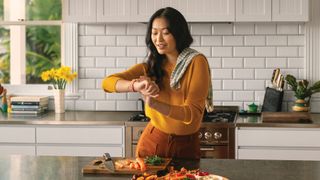 Fitbit Versa 3 review: person checking their watch while preparing vegetables in the kitchen