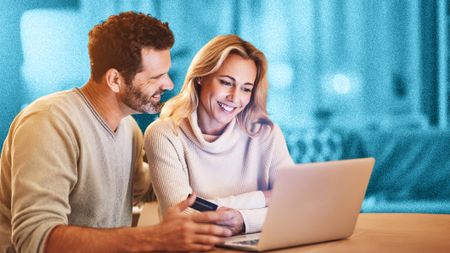 Young couple looking happy while sitting at a laptop 