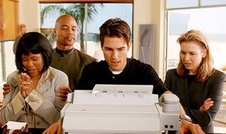 tom cruise types at a typewriter while cuba gooding jr and renee zellwegger look on in jerry maguire