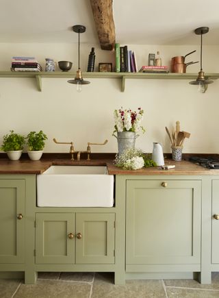 green kitchen with wooden worktops and butler's sink with brass taps