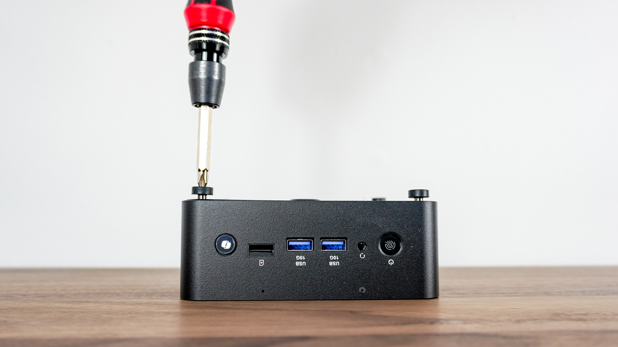 Using a screwdriver to open up the MSI Cubi NUC AI+ 2MG by unscrewing its case feet