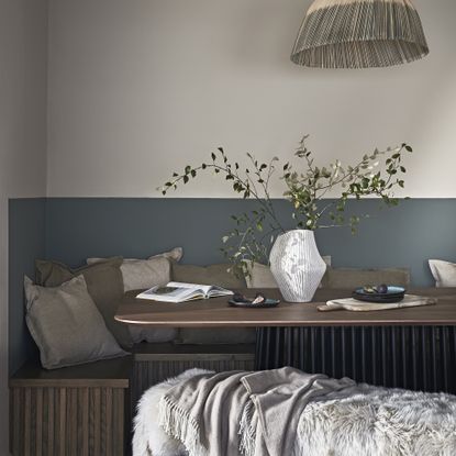 A multi-textured sensory seating nook, with a fluted wooden seating bench, soft cushions and blankets, and a rattan lamp overhead