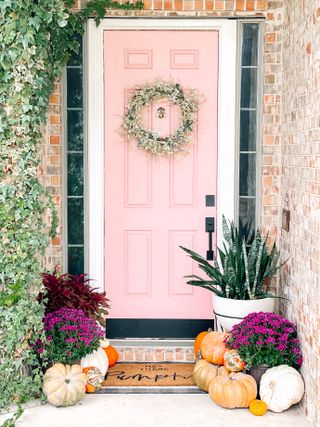 fall front door decor, pink door with wreath and pumpkins